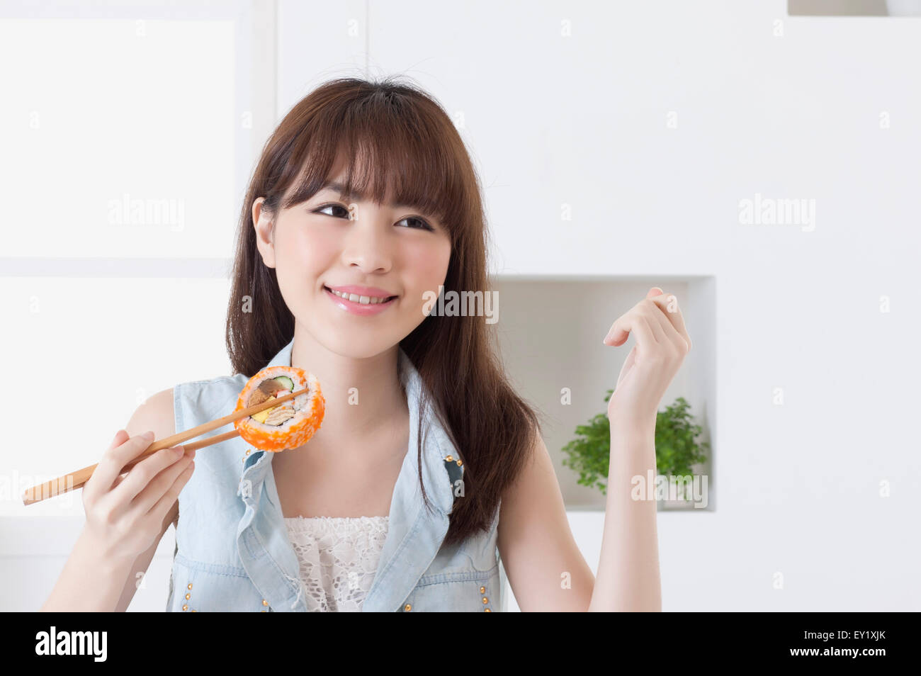 Junge Frau hält Sushi und wegschauen mit Lächeln, Stockfoto