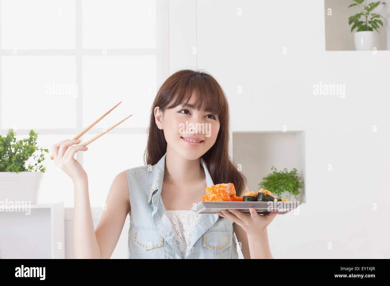 Junge Frau hält Sushi und blickte mit Lächeln, Stockfoto