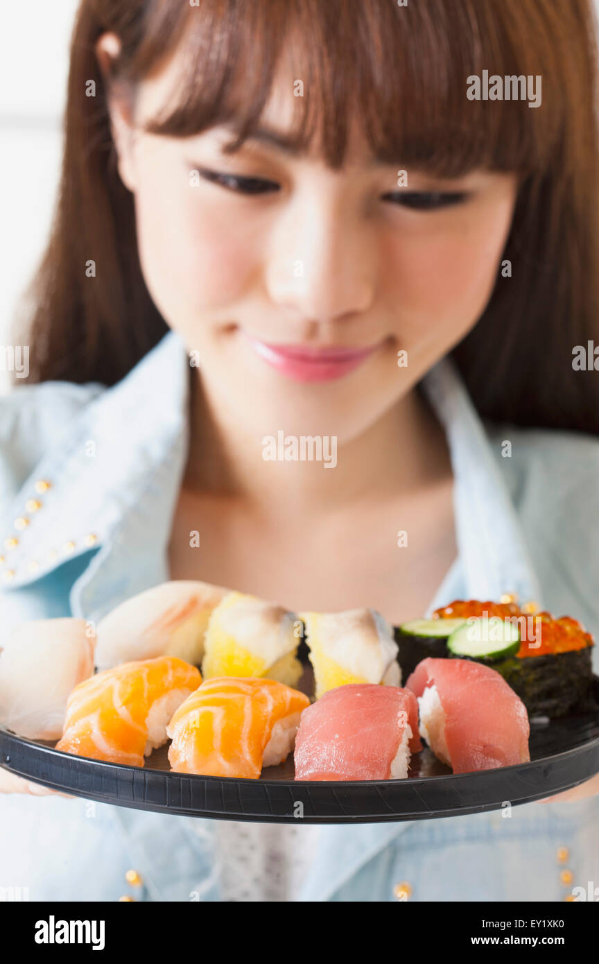 Junge Frau betrachten Sushi mit Lächeln, Stockfoto