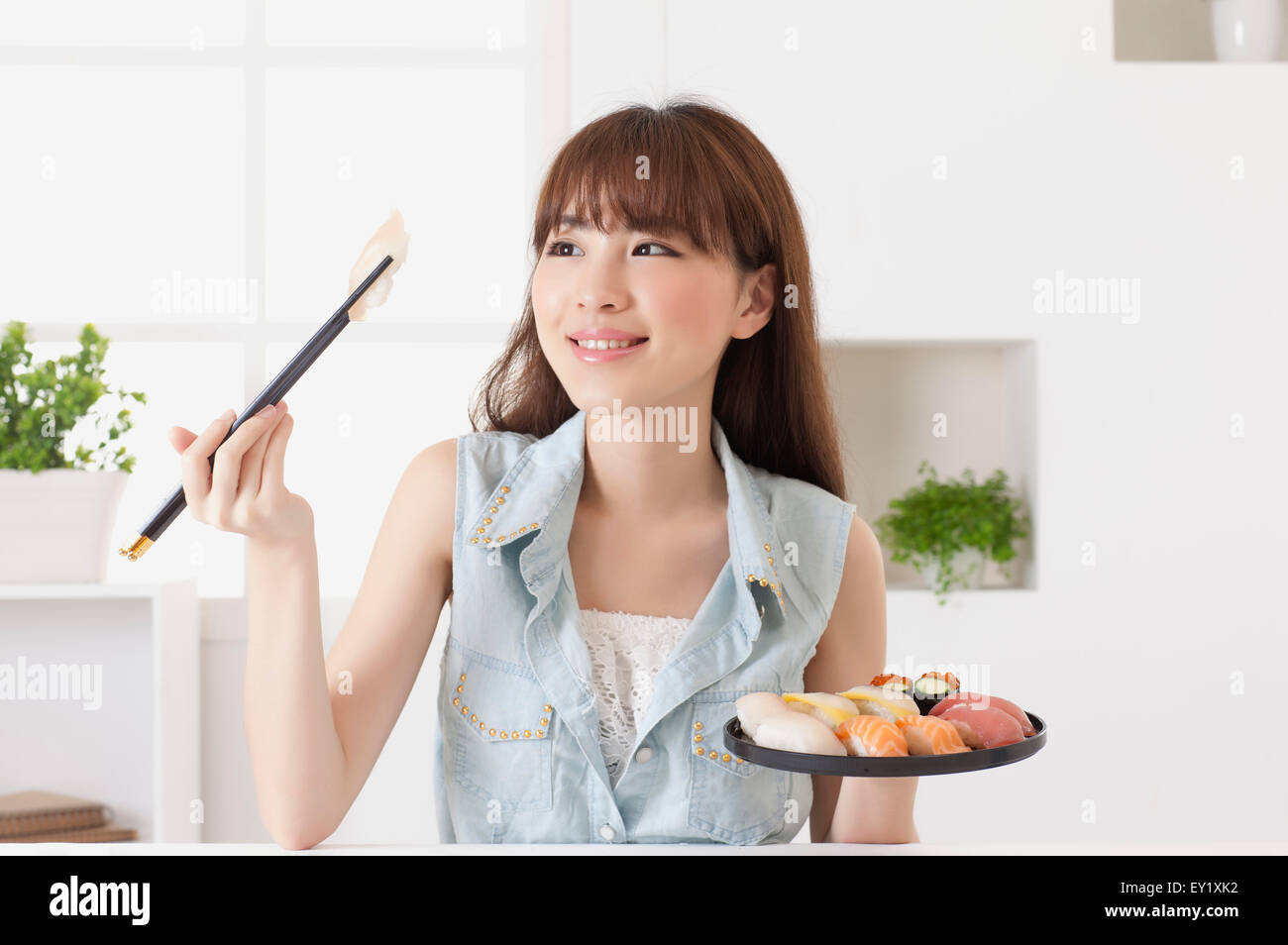 Junge Frau eine Halteplatte japanisches Essen und Ess-Stäbchen mit Lächeln, Stockfoto
