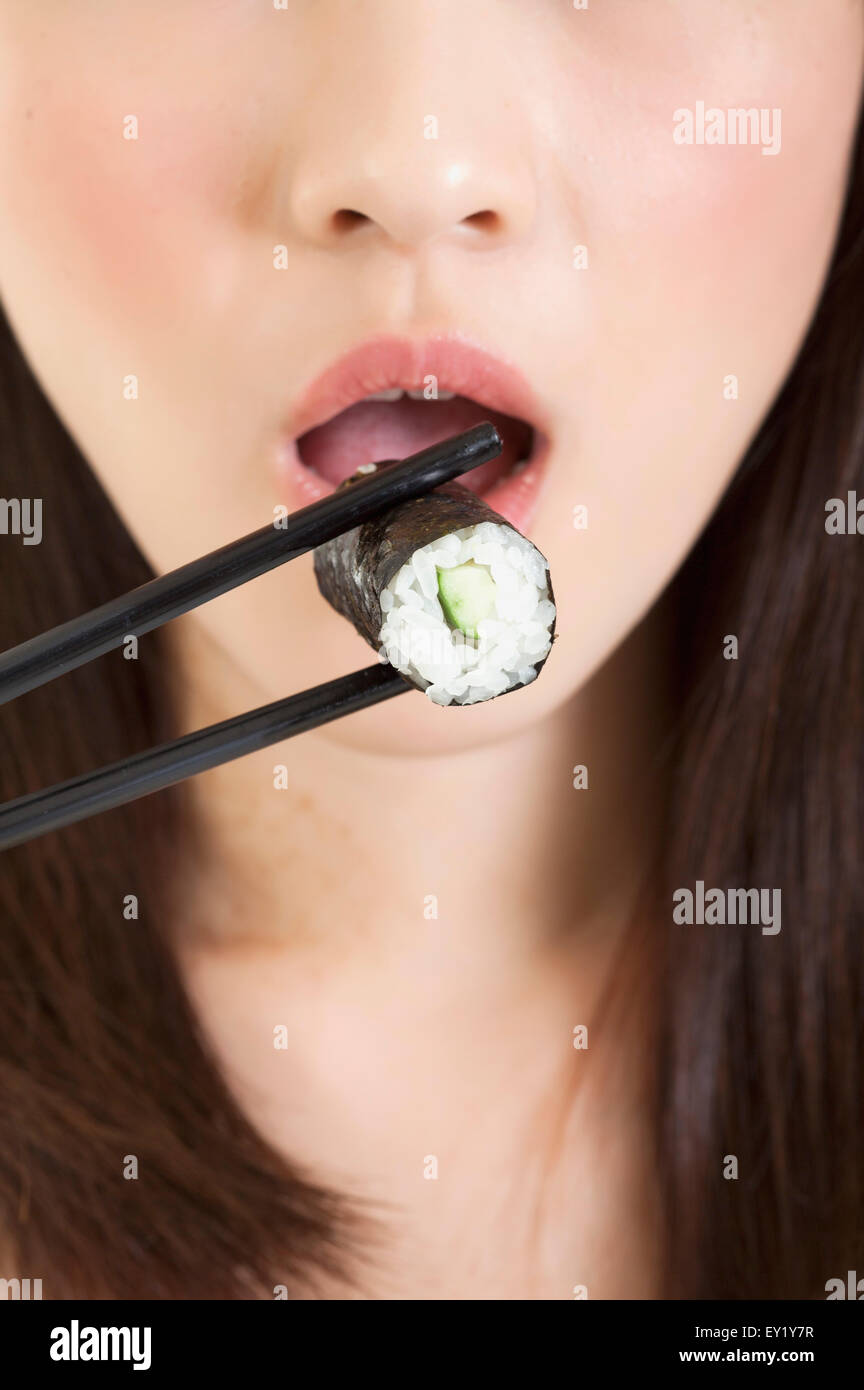 Junge Frau Essen Sushi mit Mund zu öffnen, Stockfoto