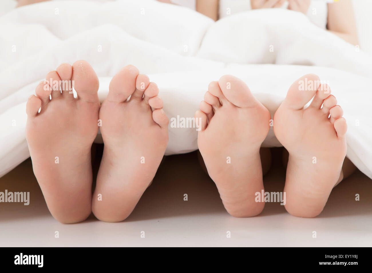 Nahaufnahme der menschlichen Füße unter der Bettdecke, Stockfoto