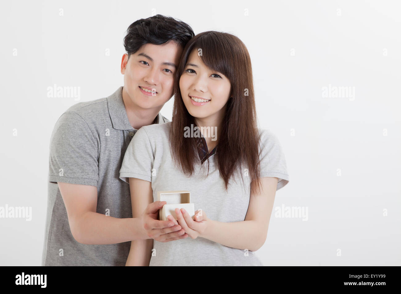 Junges Paar umarmt und lächelt in die Kamera, Stockfoto