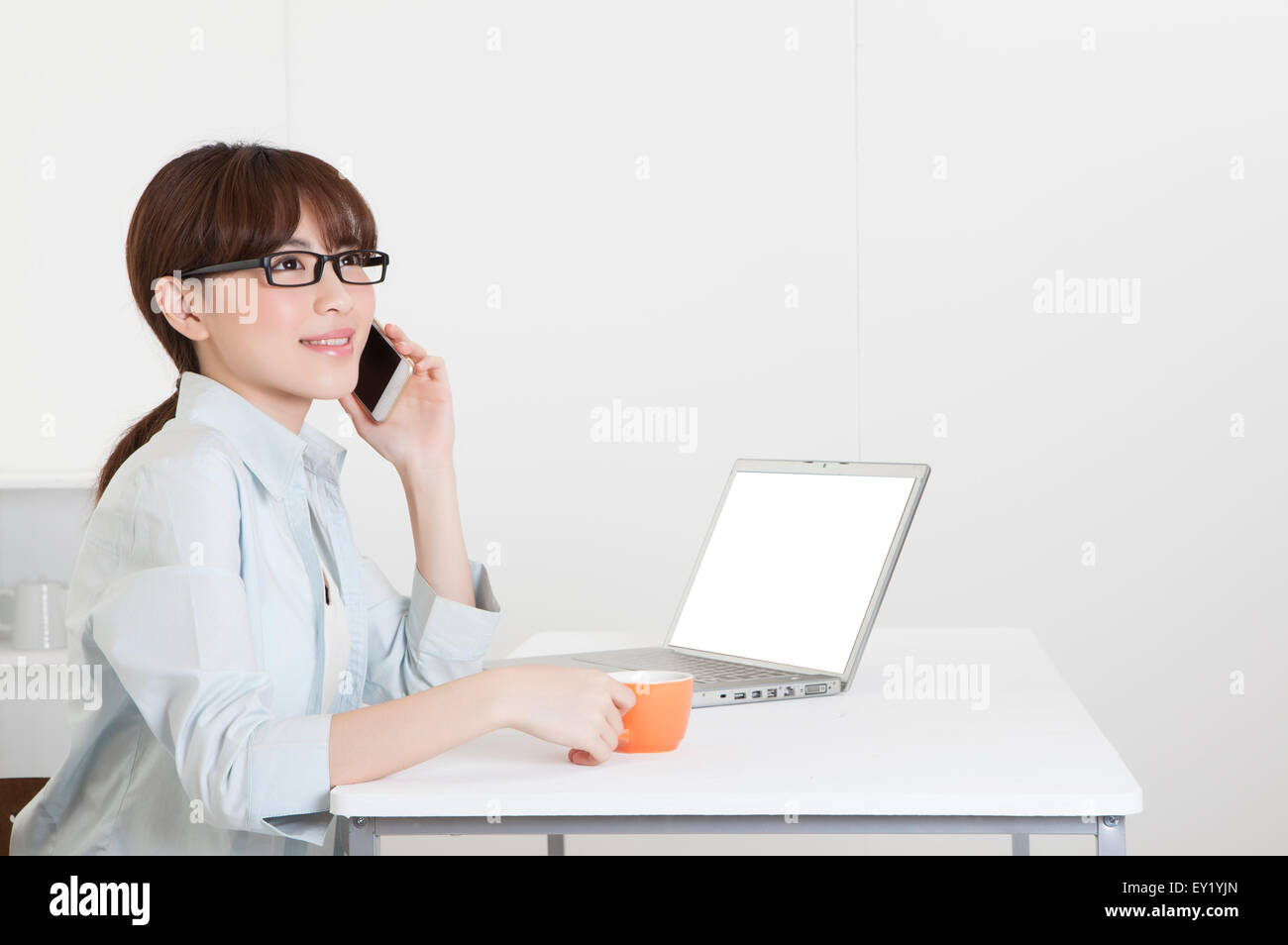 Junge Frau hält eine Kaffeetasse und auf dem Handy Stockfoto