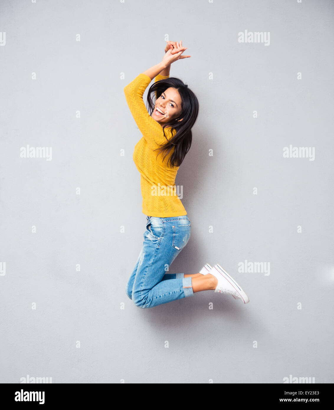 In voller Länge Portrait eine fröhliche Frau, springen über grauen Hintergrund. Blick in die Kamera Stockfoto