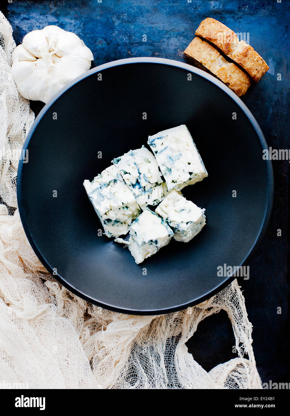 Knoblauchzwiebel und Schüssel mit gewürfelten Blauschimmelkäse Stockfoto