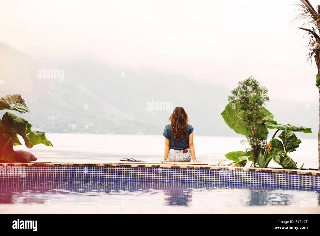 Junge Frau sitzt am Rand des Pool, San Pedro, Lake Atitlan, Guatemala Stockfoto