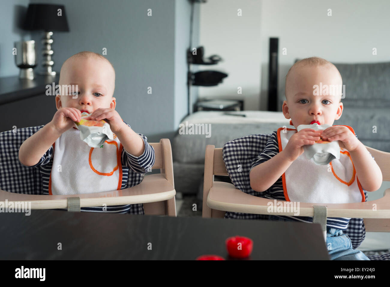 Baby Zwillinge trinken Saft in Hochstühle Stockfoto