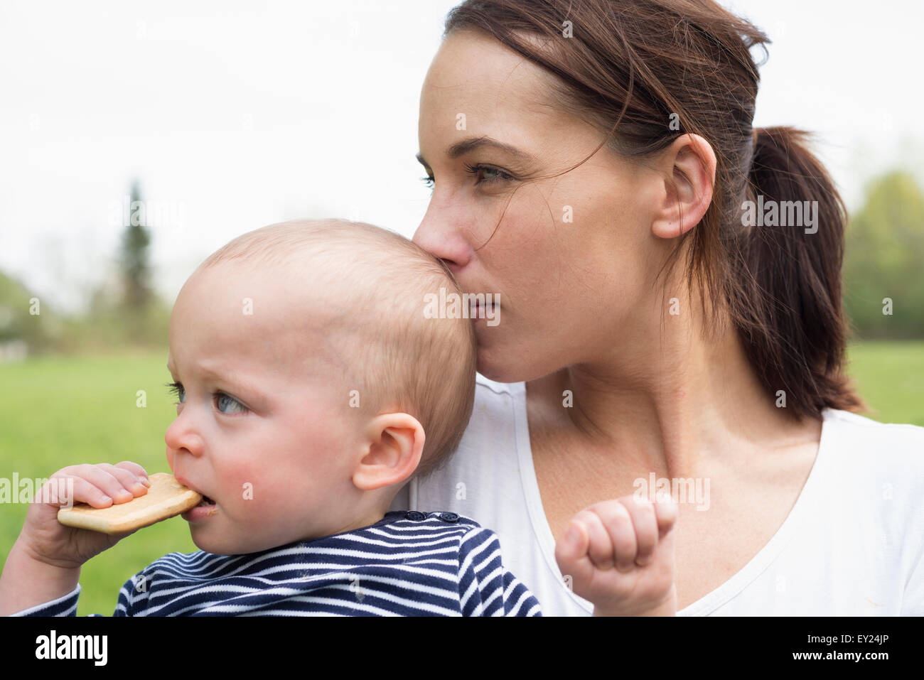 Porträt der jungen Mutter küssen Baby Sohn im Feld Stockfoto