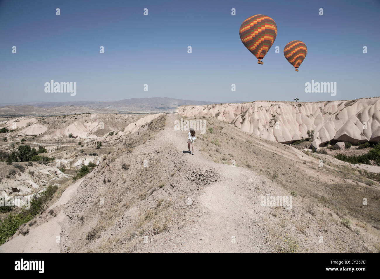 Weibliche Touristen und Heißluft Ballons in Felsformation Landschaft, Kappadokien, Anatolien, Türkei Stockfoto