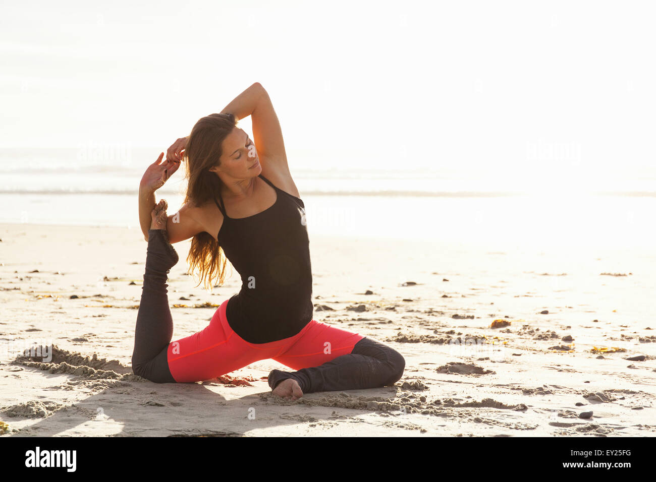 Frau in Yoga-Pose am Strand Stockfoto