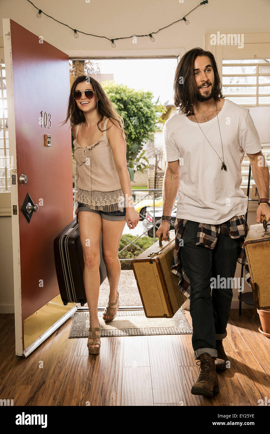 Junges Paar mit Koffern durch vordere Tür Stockfoto