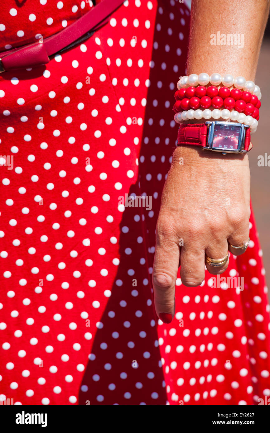 Hand der Frau trägt rot gepunkteten Kleid, Uhren und Perlen Armbänder bei Poole Oldtimer-Veranstaltung im Juli Stockfoto