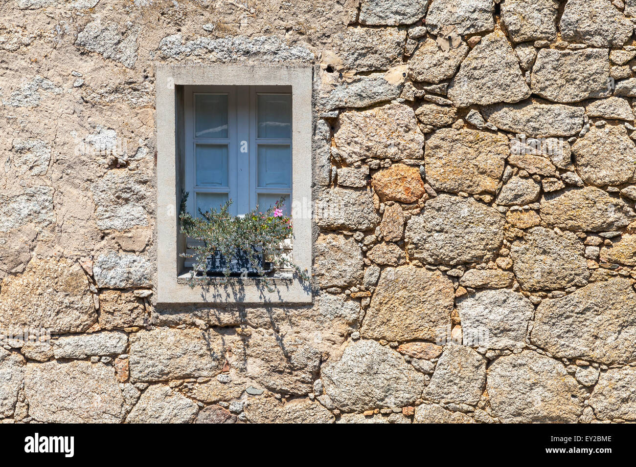 Alte Fenster mit Werk in alten grauen Steinwand, Hintergrundtextur, Korsika, Frankreich Stockfoto