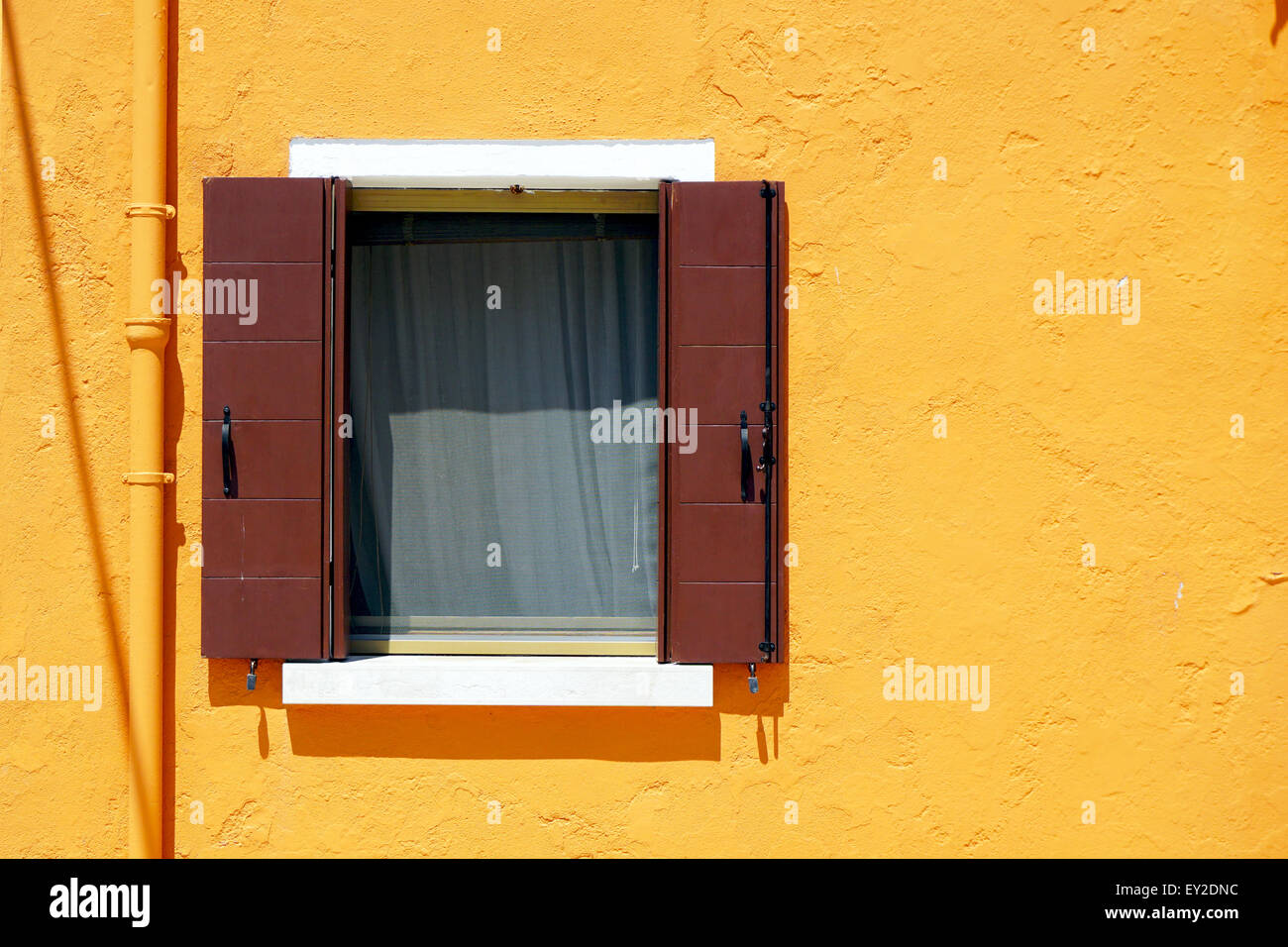 Braun-Fenster in Burano auf orange Farbe Wand Gebäudearchitektur, Venedig, Italien Stockfoto