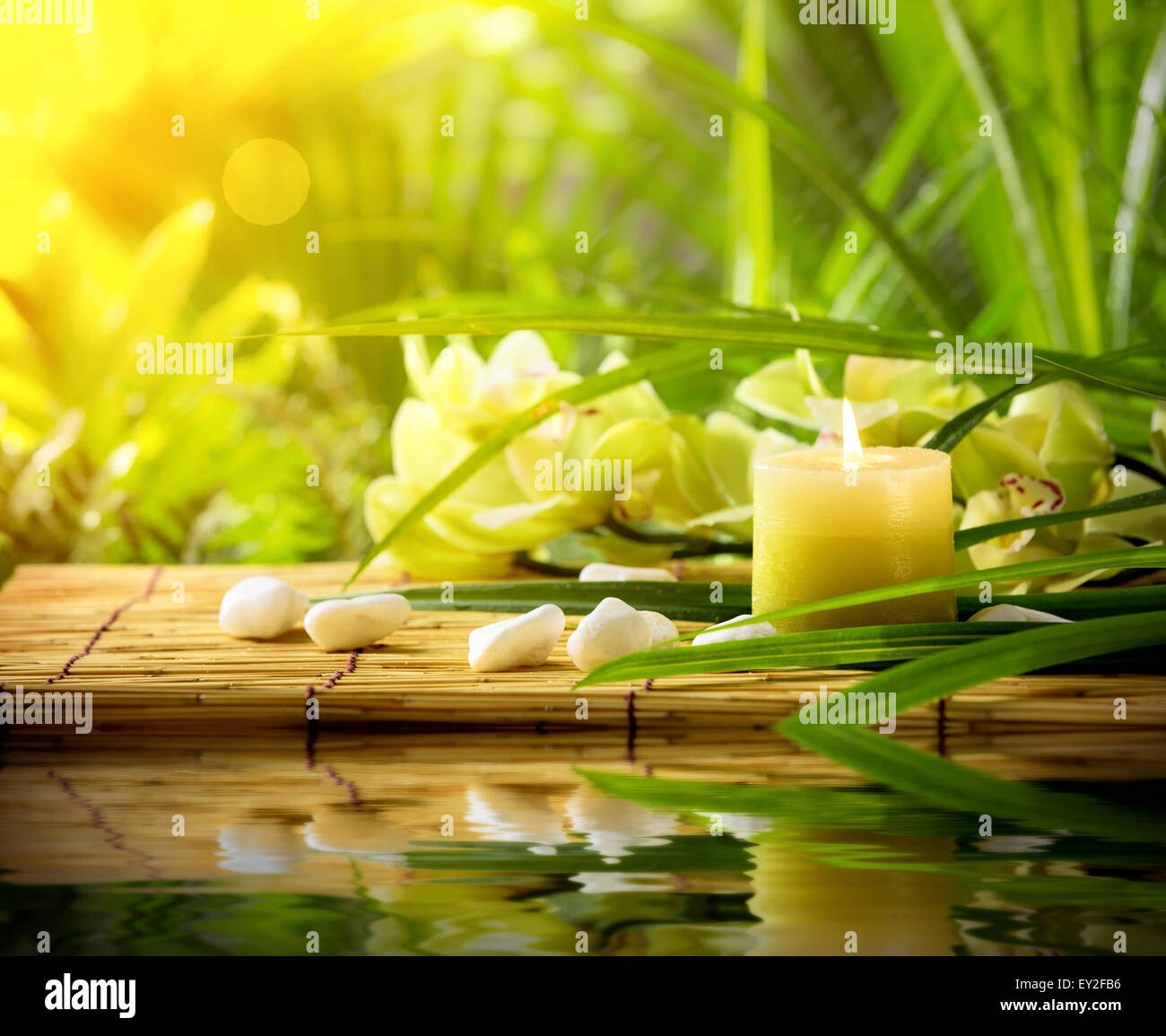 Spa-Stillleben mit Kerze, Kieselsteine und Orchidee auf Bambusmatte Stockfoto