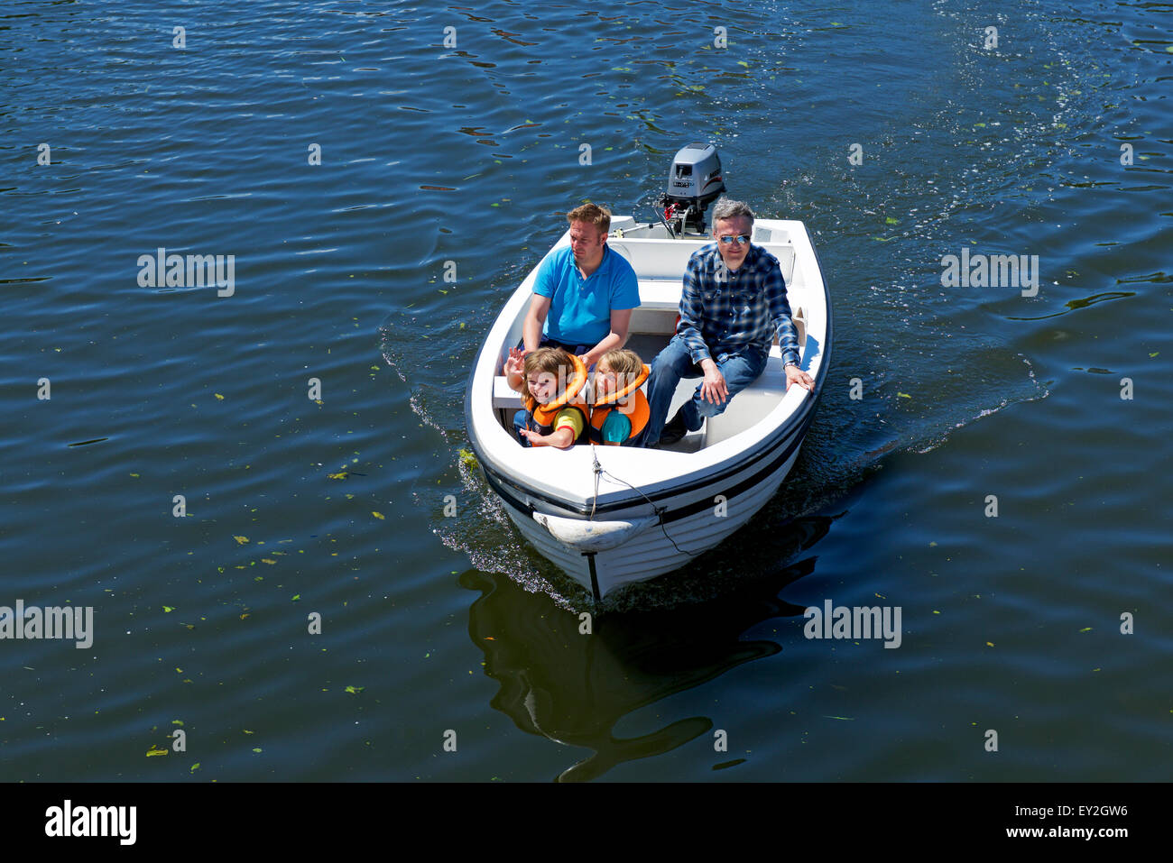 Zwei Männer, zwei Kinder, im kleinen Schlauchboot mit Außenbordmotor, England UK Stockfoto