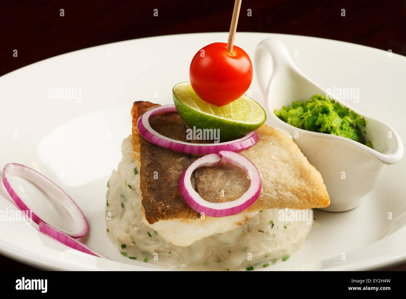 Risotto mit Wolfsbarschfilet und grüne Erbse Mash serviert Stockfoto