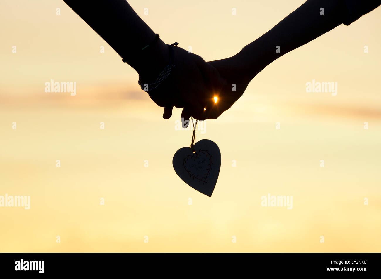 Junge Mädchen und jungen Hände halten ein Herz. Silhouette Stockfoto