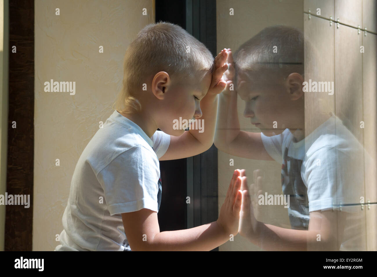 Traurig traurig warten langweilig deprimiert Kind (junge) in der Nähe eines Fensters, Reflexion. Stockfoto