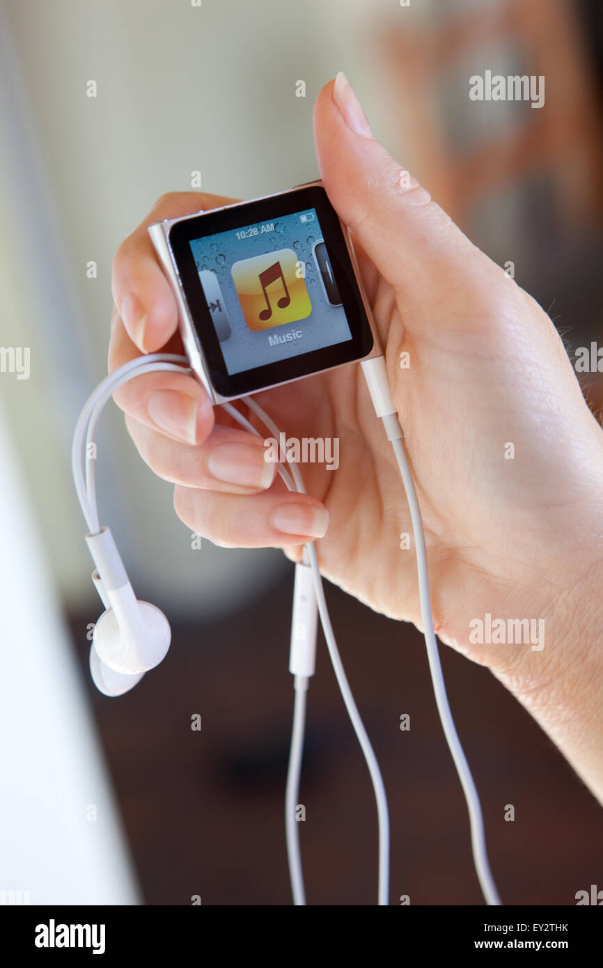 Nahaufnahme von einem Apple iPod Nano mit Kopfhörern, hielt in einem Womans Hand zeigt die iTunes-Musik-Bildschirm. Stockfoto