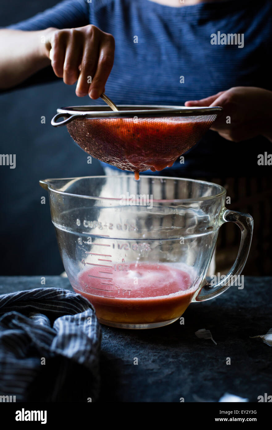 Seiving Tomaten über einem Mess Krug. Stockfoto