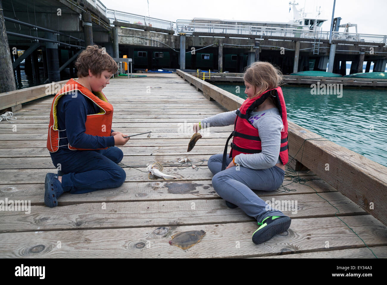 Ein Junge und ein Mädchen in Alaska teilen einen Moment mit einem Fisch. Stockfoto