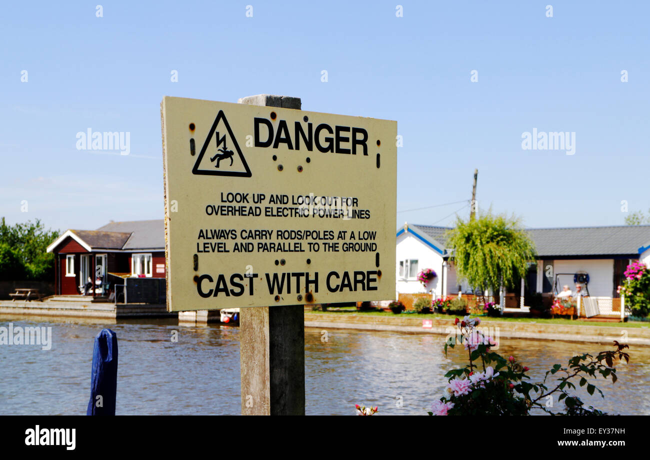 Gefahrenzeichen für Angler über Freileitungen durch den Fluß Thurne auf Repps, Norfolk, England, Vereinigtes Königreich. Stockfoto