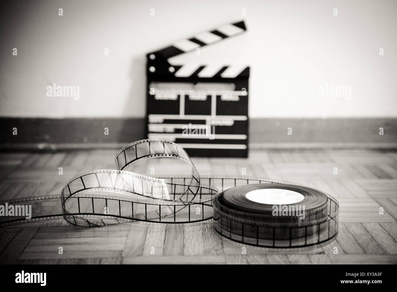 35 mmKinoFilmrolle und aus Fokus Film Klappe im Hintergrund auf Holzboden in Vintage schwarz