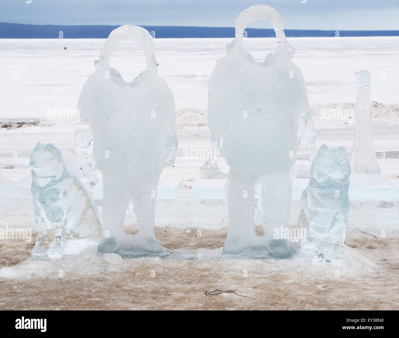 Eis-Statuen von Männern mit Hunden am See Stockfoto