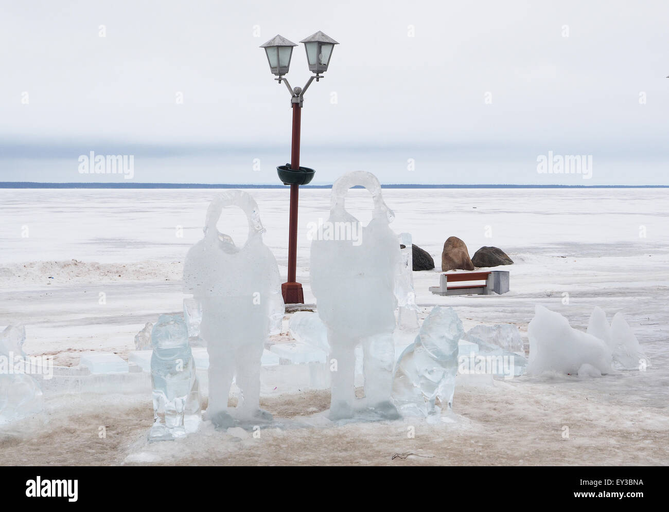Eis-Statuen von Männern mit Hunden am See Stockfoto