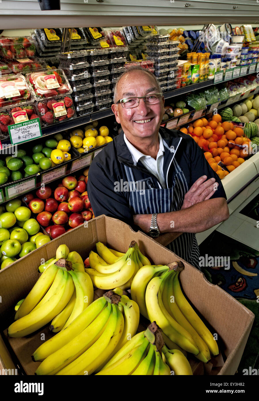 Ein Mann steht in einem Lebensmittelladen neben einem Display von frischem Obst und Gemüse. Stockfoto