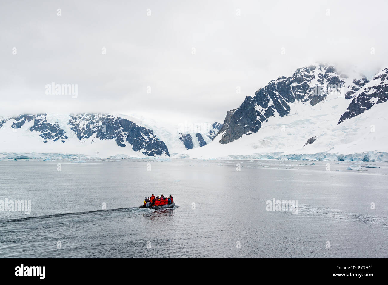 Gruppe von Personen, die über den Ozean in die Antarktis in einem Schlauchboot, schneebedeckte Berge im Hintergrund. Stockfoto