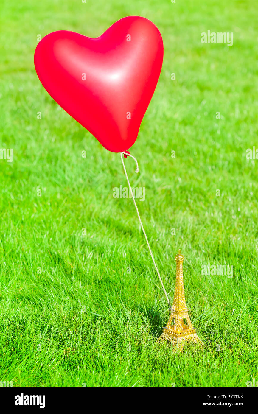 Liebe Paris - Miniature Eiffel-Turm auf einer Wiese mit einem roten Herz geformten Ballons gebunden Stockfoto
