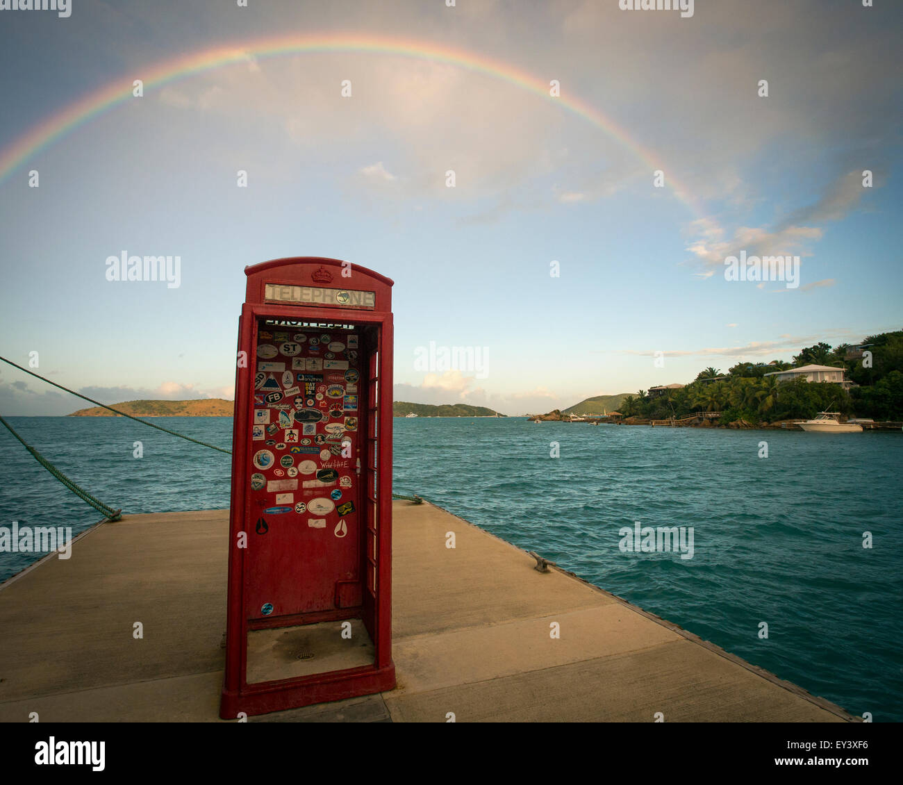 Regenbogen über eine rote Telefonzelle stehen auf einem Steg am Meer. Stockfoto