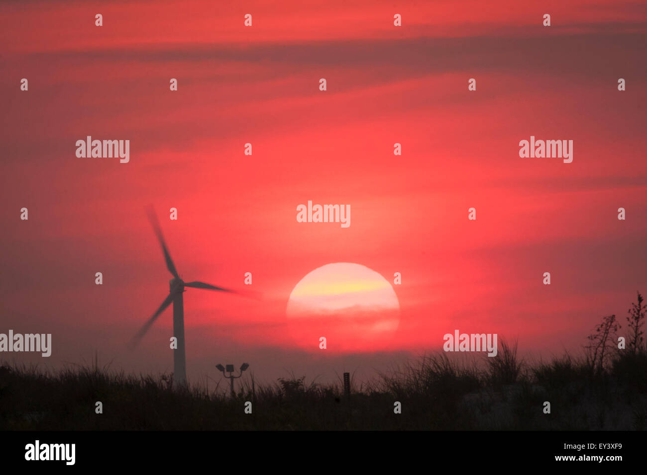 Landschaft bei Sonnenaufgang mit einer Windkraftanlage vor einem roten Himmel abhebt. Stockfoto
