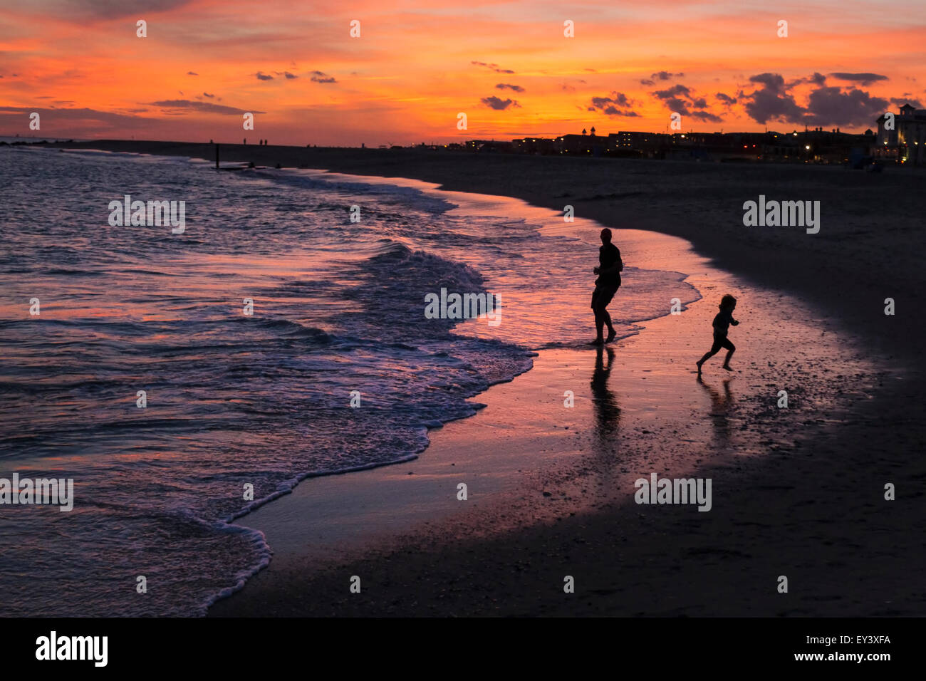 Vater und Sohn spielt auf einem sandigen Strand bei Sonnenuntergang. Stockfoto