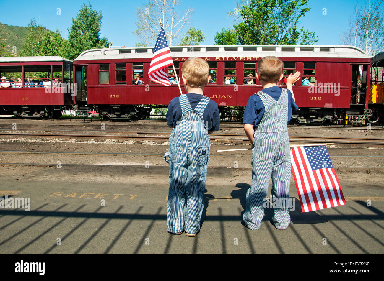 Jungen mit amerikanischen Fahnen winken Fahrgäste im Zug Stockfoto