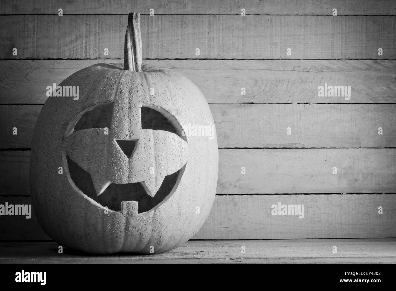 Halloween-Kürbis auf hölzernen Hintergrund auf schwarz und weiß Stockfoto