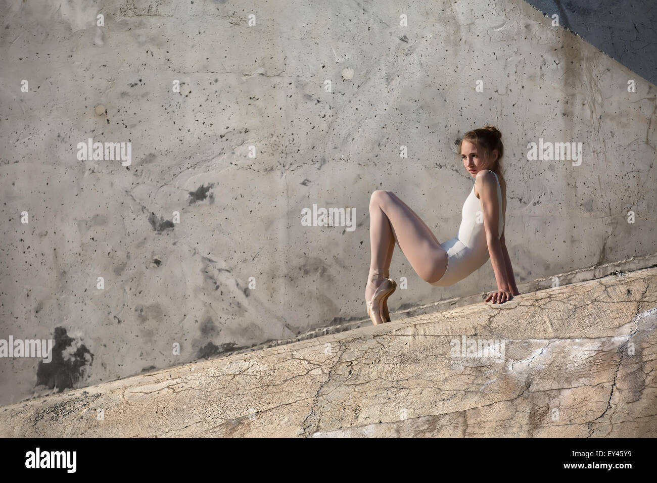 Schlanke Tänzerin sitzt in einer Ballett-pose Stockfoto