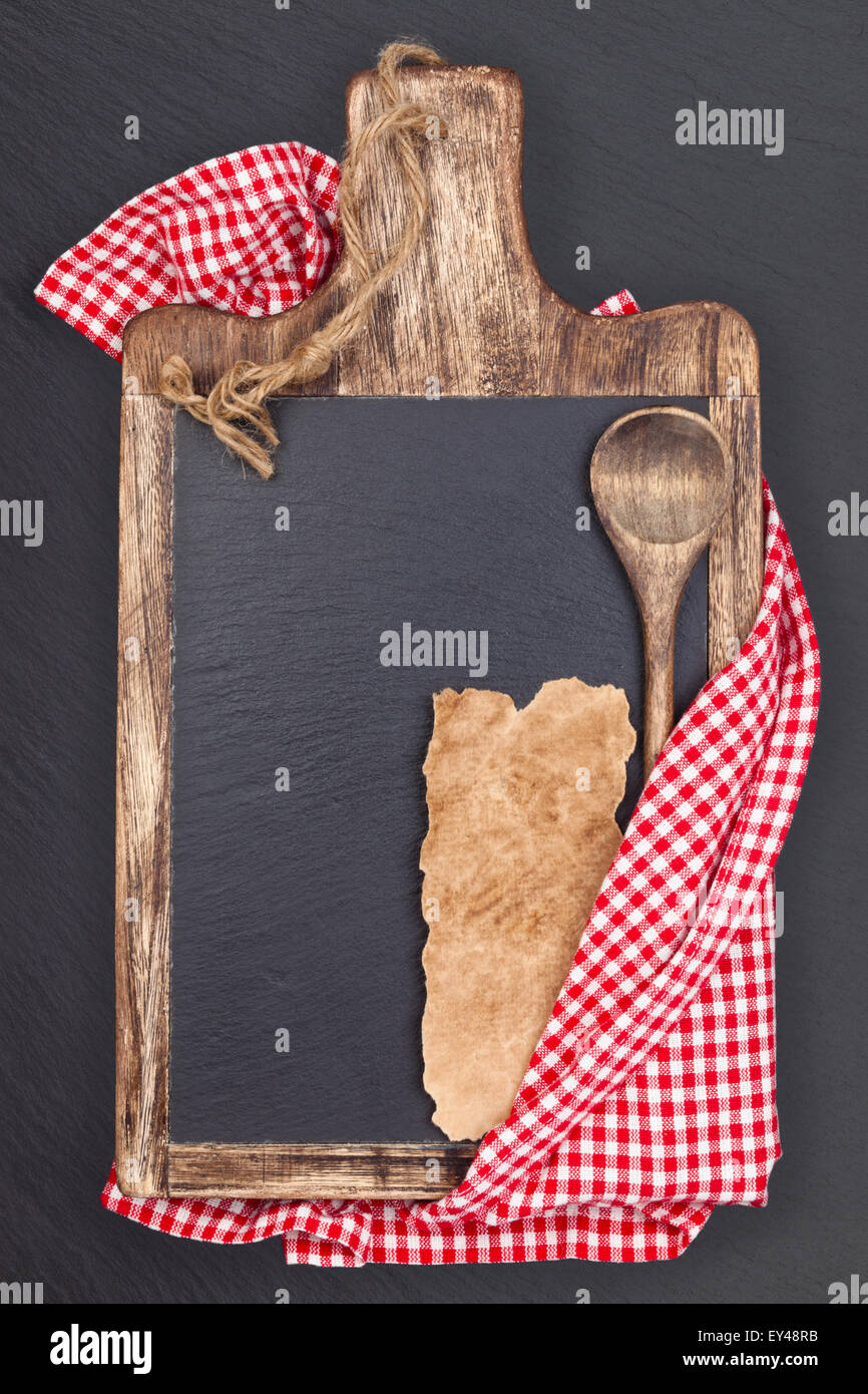 Schneidebrett, Tischdecke, Holzlöffel und Stück Papier der alten Rezept. Stockfoto