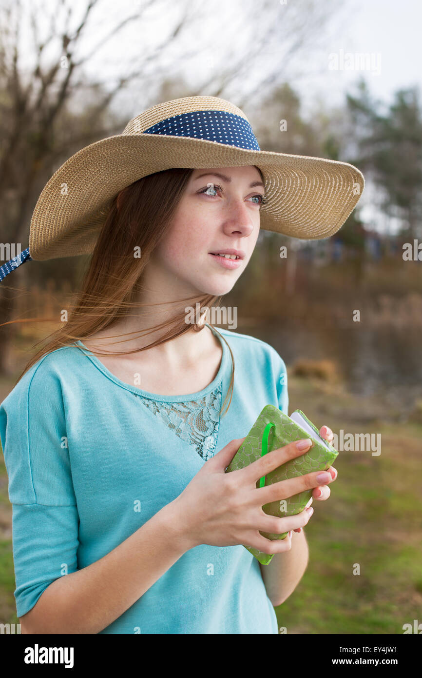 Sommersprossige Mädchen mit Hut stehend mit Hinweis und wegsehen bei windigem Wetter Stockfoto