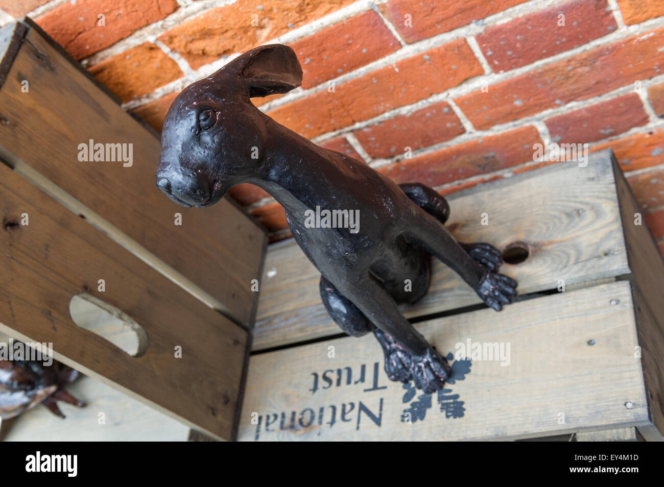 Schwarz lackiertes Messingmodell eines Hasen, der auf einer Holzkiste sitzt. Stockfoto