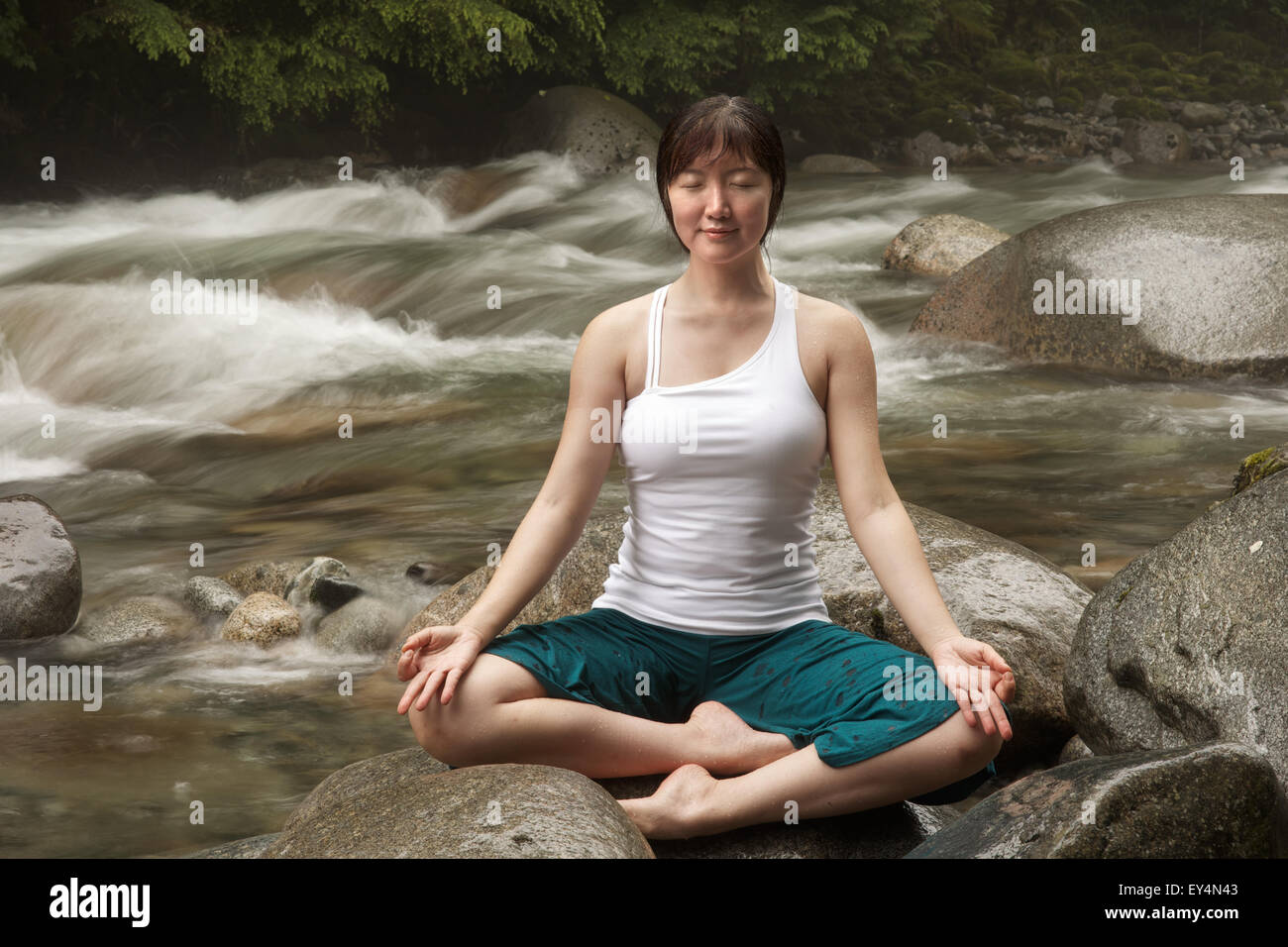 Asiatische Frau Durchführung einfach darstellen (Sukhsana) Yoga am Fluss, Lynn Valley, British Columbia, Kanada Stockfoto