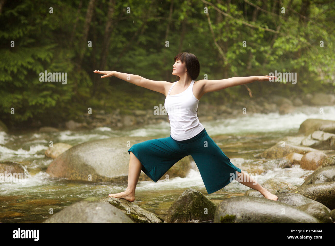 Asiatische Frau Durchführung Krieger II Pose Yoga (Virabhadrasana) am Fluss, Lynn Valley, British Columbia, Kanada Stockfoto