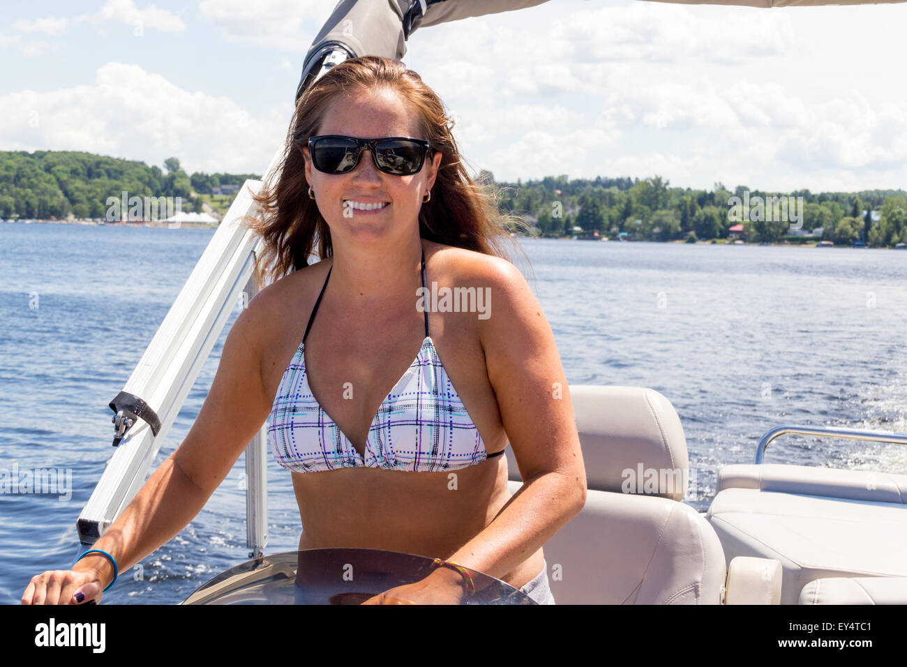 Lächelnde Frauen fahren ein Ponton-Boot auf einem See im Sommer Stockfoto