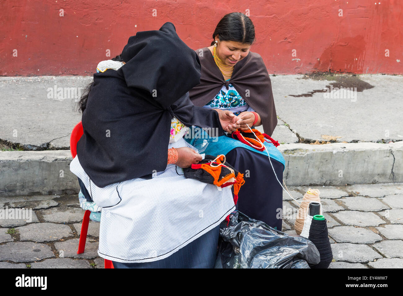 Einheimische Frauen Hand stricken bunte Mützen im lokalen Markt. Otavalo, Ecuador. Stockfoto