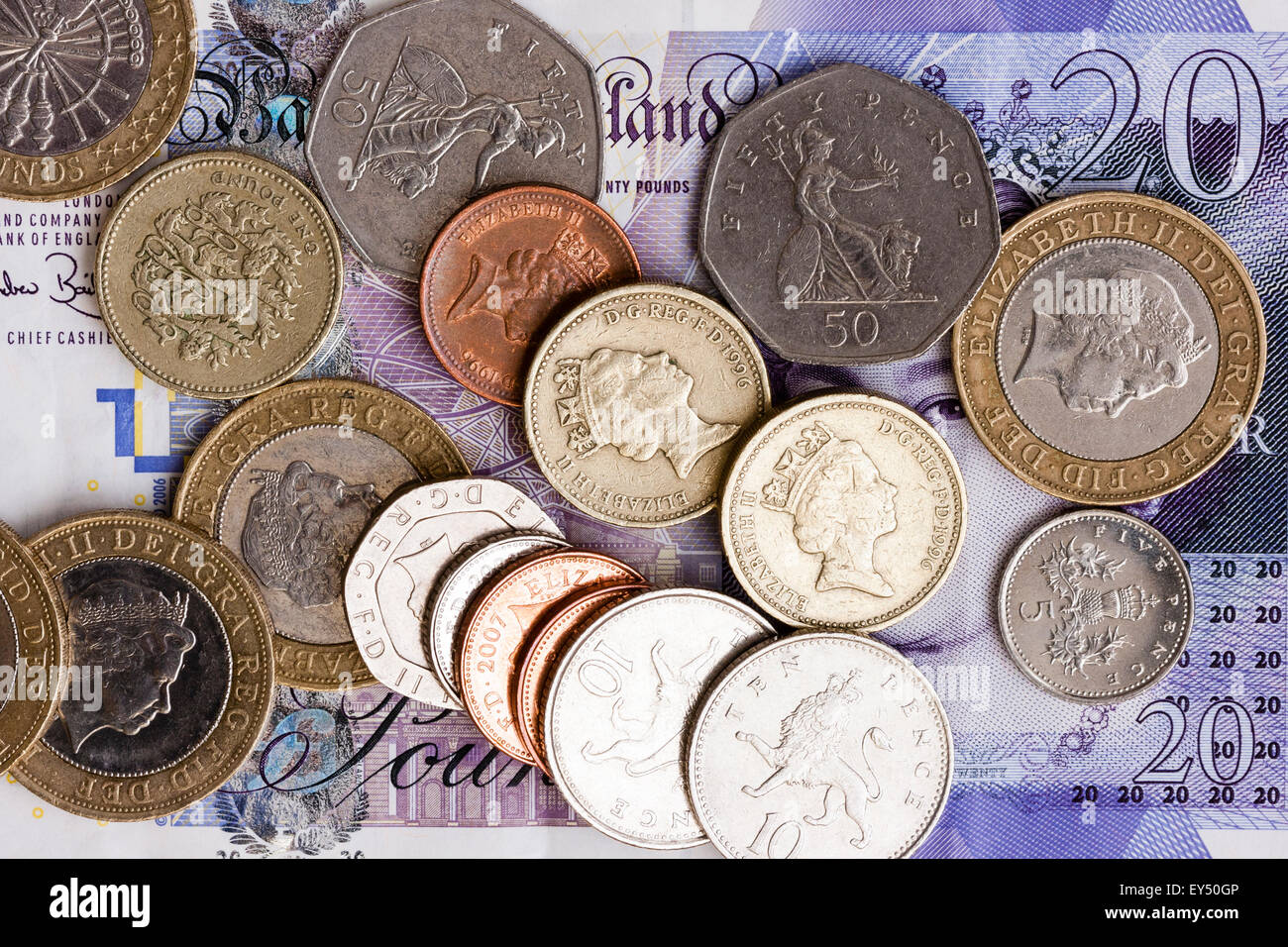 Britische Währung. Diverse Münzen auf £ 20 Banknote verstreut. Mit der Pre-2017 £ 1 Münzen, Stockfoto