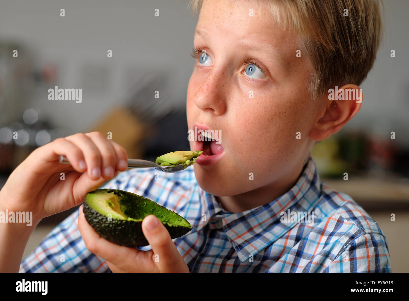 Ein Kind essen eine Avocado mit einem Löffel als gesunder snack Stockfoto