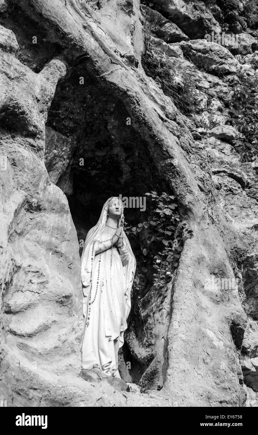 Statue der Madonna platziert in einem Hohlraum in der Felswand. Stockfoto